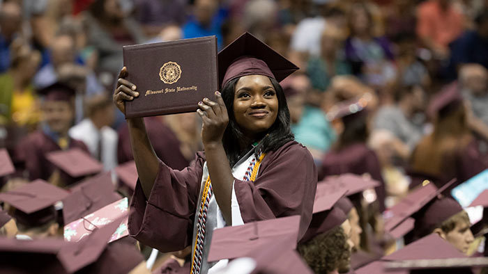 A Missouri State graduate holding their diploma